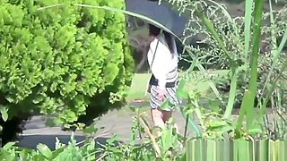 Asian chick pees outdoors in rain