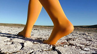 Barefoot walking by dried up lake in yellow pantyhose