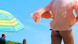 Playful nude beach girl caught on camera tanning